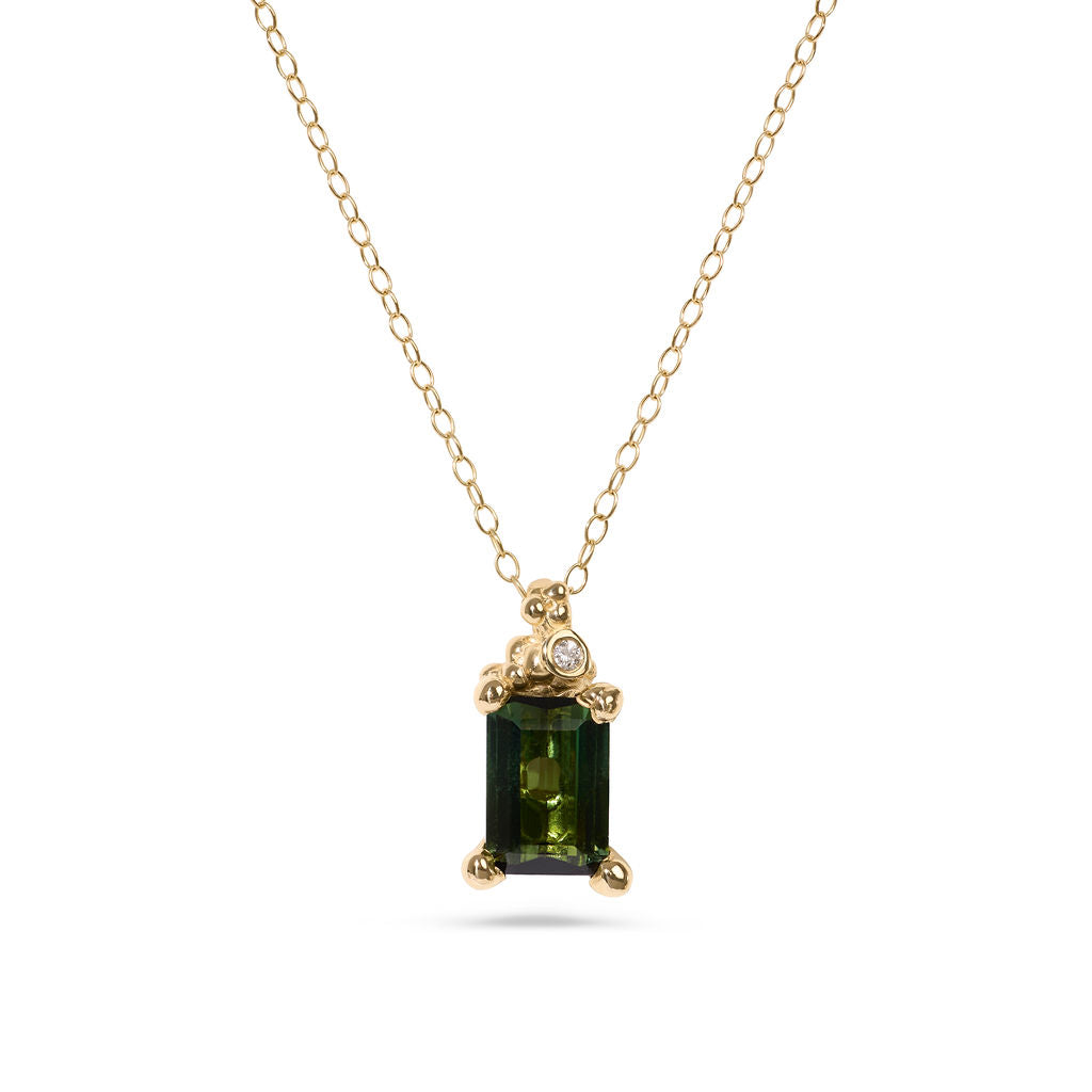 Gold necklace with a green gemstone pendant on a white background
