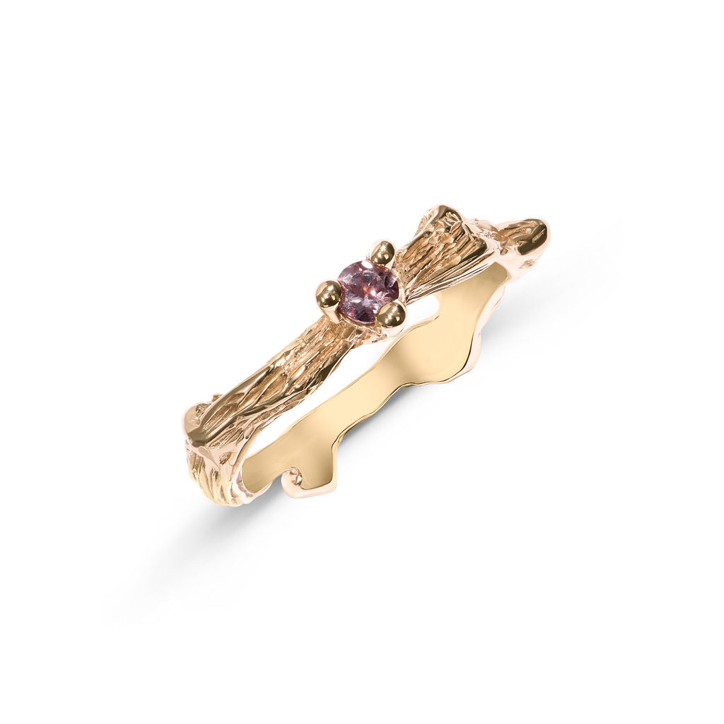 Gold ring with a pink brown gemstone on a white background