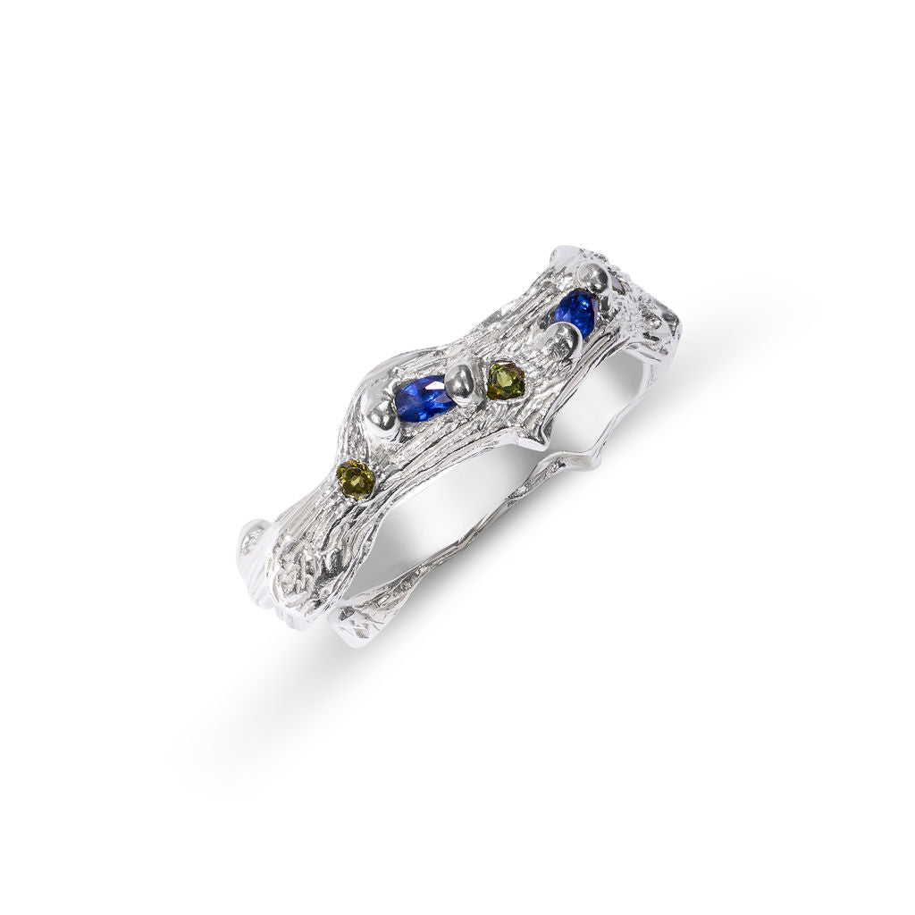 Silver ring with embedded blue and green gemstones on a white background