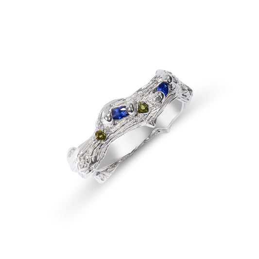 Silver ring with embedded blue and green gemstones on a white background